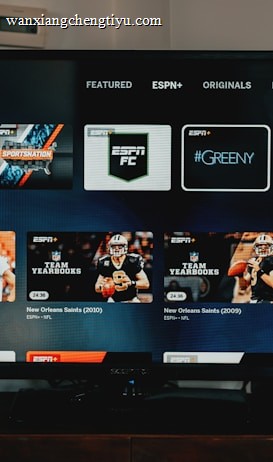A television screen displaying the ESPN+ streaming interface with various sports-related shows and categories. The screen includes sections such as 'Browse by Shows' and 'Best of Drew Brees' with thumbnails of sports programs featuring athletes in action and analysts.